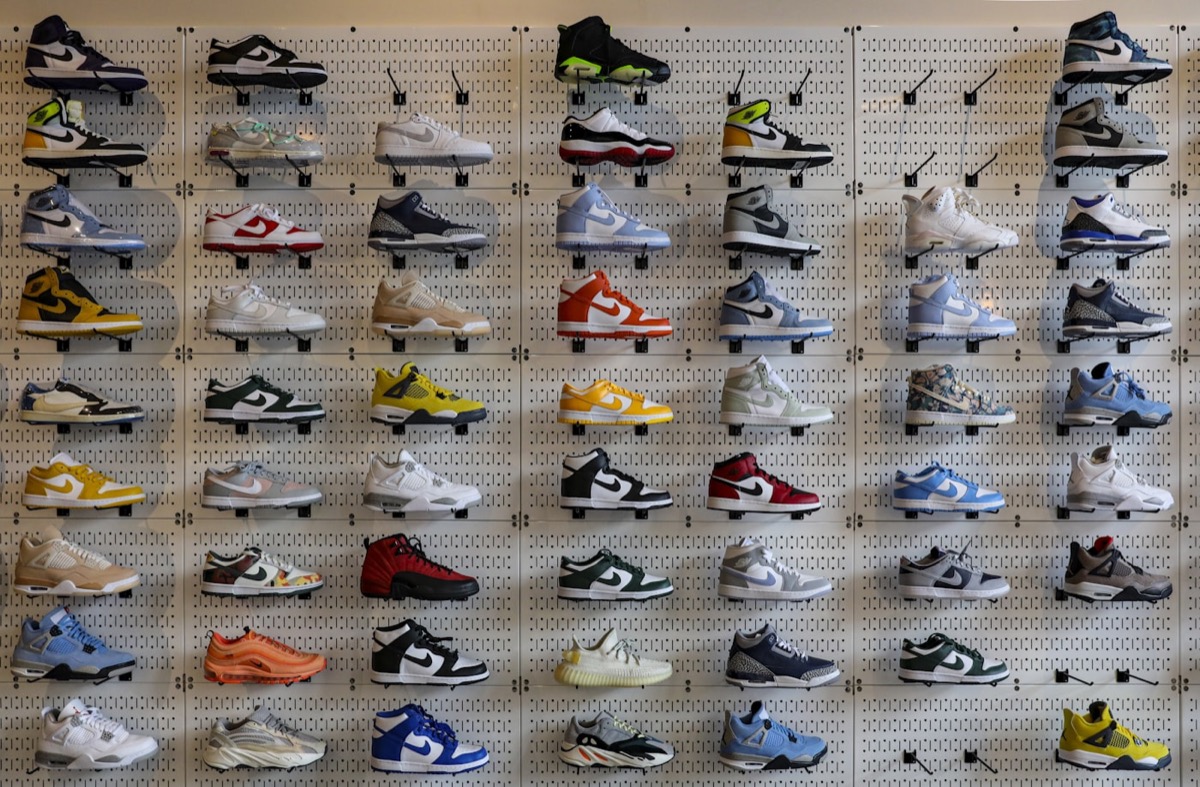 A retail wall stacked with rows of sneakers on white pegboard.